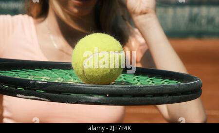 Mädchen hält einen Tennisschläger mit einem Tennisball darauf Stockfoto