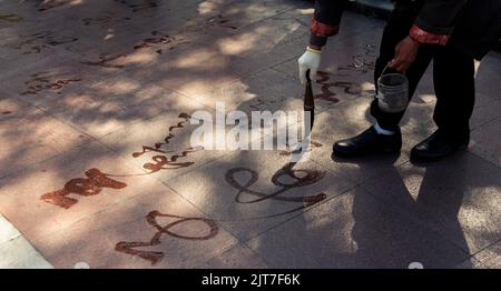 Ein Mann, der in Shanghai, China, Kalligraphie auf dem Boden schreibt Stockfoto