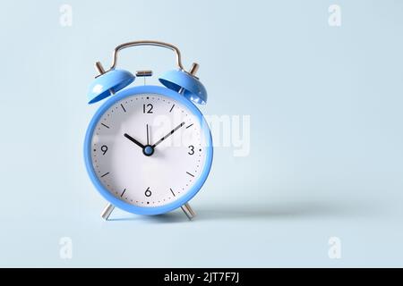 Altmodischer blauer Wecker auf blauem Hintergrund. Nahaufnahme. Speicherplatz kopieren. Stockfoto