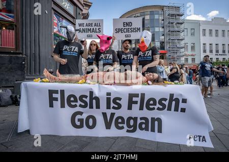 London, Großbritannien. 27.. August 2022. PETA-Tierrechtler führen auf dem Leicester Square einen Anti-Fleisch-Protest durch, bei dem „Tiere“ am Körper einer jungen Frau fessen. PETA fordern mehr Verbraucher, vegan zu gehen und auf pflanzliche Lebensmittel umzusteigen. Kredit: Guy Corbishley/Alamy Live Nachrichten Stockfoto