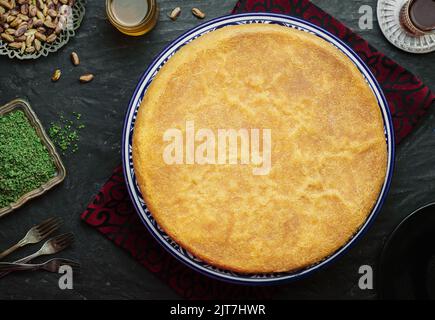 Arabische Küche: Traditionelles Gebäck aus dem Nahen Osten und das berühmte Dessert „Kunafa“ im Ramadan. Serviert mit Pistazie, Honigsirup und einer Tasse Tee. Stockfoto