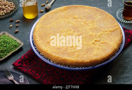 Arabische Küche: Traditionelles Gebäck aus dem Nahen Osten und das berühmte Dessert „Kunafa“ im Ramadan. Serviert mit Pistazie, Honigsirup und einer Tasse Tee. Stockfoto