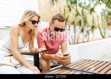 Junges Paar, das in einem Café sitzt und Smartphones benutzt. Studenten während der Pause im Café-Platz Stockfoto