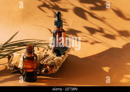 Kosmetische Tropfflasche Stein Podium Sockel. Brauner Hintergrund mit harten Schatten vom Pflanzenzweig Stockfoto