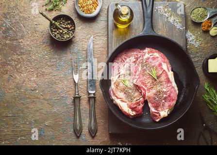 Frisches rohes Rindersteak auf Holzbrett mit Butter, Gewürz und Rosmarin. Nahaufnahme mit Kopierbereich. Stockfoto