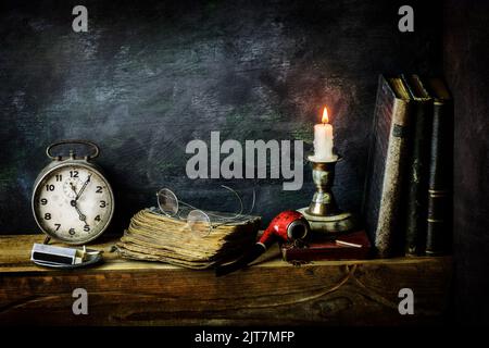 Klassisches Stillleben mit Vintage-Büchern, die mit alter Uhr, Pfeife, Gläsern und beleuchteten Kerzen auf rustikalem Holzhintergrund platziert sind. Stockfoto