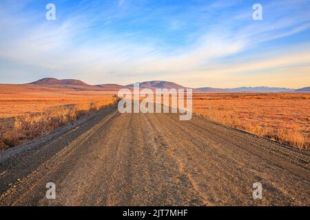 Eine lange flache Strecke des Dempster Highway in Richtung Norden über den Blackstone Hochland in Kanadas Yukon Territory. Stockfoto