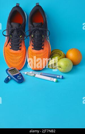 Orangefarbene Sneakers, Früchte, Maßband, Glucometer und Insulin-Spritzenstifte auf blauem Hintergrund Stockfoto