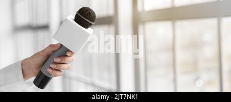 Weibliche Journalistin mit Mikrofon im Innenbereich Stockfoto