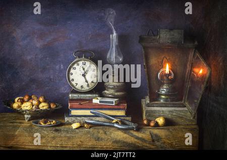 Klassisches Stillleben mit Vintage-Büchern, die mit alter Uhr, beleuchteten antiken Lampen und Nussknacker auf rustikalem Holzhintergrund platziert sind. Stockfoto