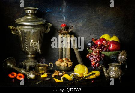 Klassisches Stillleben mit Vintage-Büchern, die mit altem silbernen Samowar, Kerzenständern, frischen Früchten, einer Tasse Tee, Teedose und Nüssen auf Vintage-Hintergrund platziert sind. Stockfoto