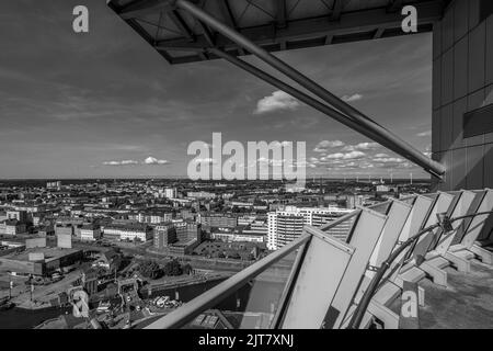 Eine Graustufenaufnahme eines Stadtbildes und eines Flusses unter bewölktem Himmel von einem hohen Turm aus Stockfoto