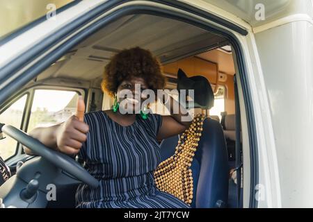 Fröhliche afroamerikanische Frau, die am Lenkrad sitzt und ein Schild mit der Aufschrift „OK“ zeigt. Hochwertige Fotos Stockfoto