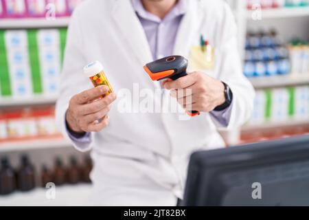 Junger hispanischer Mann Apotheker Scannen Pillen Flasche in der Apotheke Stockfoto