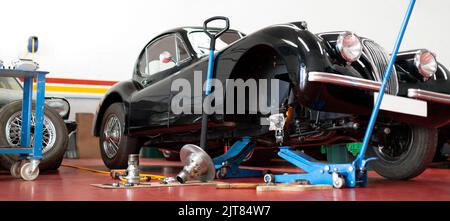 Panoramablick auf antikes Automobil, das in der Mechaniker-Werkstatt repariert wird. Wartung und Restaurierung von Oldtimern. Stockfoto