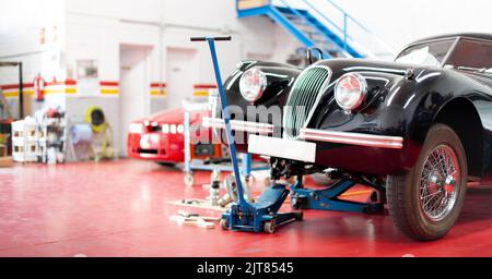 Panoramablick auf das Innere einer Garage. Oldtimer wird repariert. Platz für Text. Stockfoto