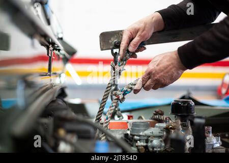 Detail der Hände eines Mechanikers, der ein Auto repariert. Nicht erkennbare Person, die in einer Werkstatt arbeitet. Stockfoto