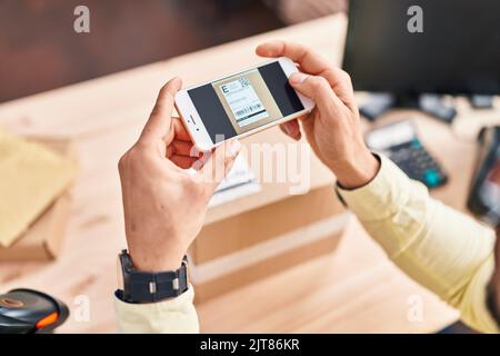 Junger hispanischer Mann E-Commerce-Business-Mitarbeiter Scannen Etikett mit Smartphone im Büro Stockfoto