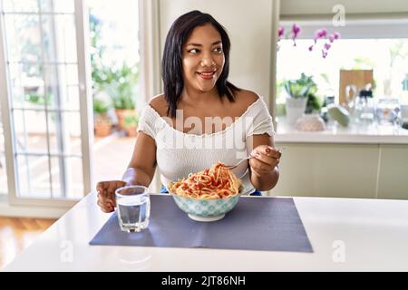 Hispanische Brünette Frau essen Spaghetti in der Küche Stockfoto