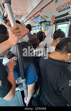 Eine vertikale Aufnahme von Menschen mit Masken in einem überfüllten Bus bei der Coronavirus-Pandemie in Peking, China Stockfoto