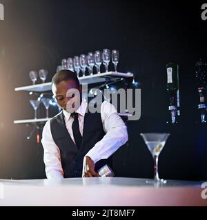 Ich serviere nur das Beste. Ein gut gekleideter Barkeeper, der hinter dem Tresen steht. Stockfoto