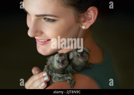 Auf Mummys Schulter aufgestampft. Eine attraktive junge Frau, die mit zwei Schweinchen-Murmeltiere posiert. Stockfoto