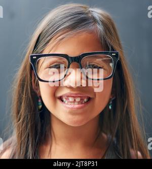 Die Freuden, ein Kind zu sein. Studioportrait eines kleinen Mädchens, das eine Brille vor dunklem Hintergrund trägt. Stockfoto