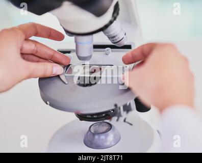 Zeit für die Untersuchung einer neuen Probe. Nahaufnahme eines Wissenschaftlers, der ein Mikroskop benutzt, während er in einem Labor sitzt. Stockfoto