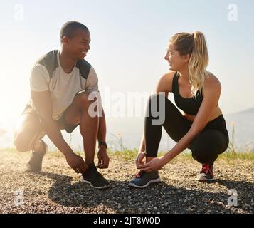 Sie teilen die gleichen Fitnessziele. Ein fitness junges Paar bindet ihre Schnürsenkel vor einem Lauf im Freien. Stockfoto