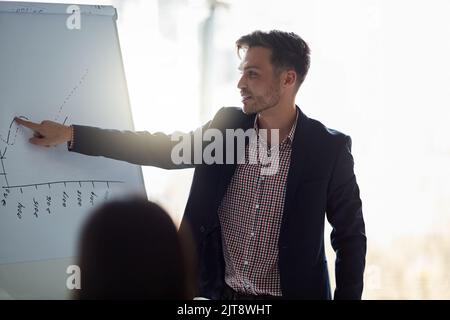 Schauen Sie sich einfach diesen Umsatzschub an. Ein gut gekleideter Geschäftsmann, der seinen Kollegen im Sitzungssaal eine Präsentation gibt. Stockfoto