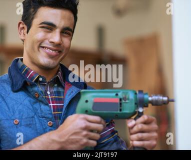 Sie sind mehr als Werkzeuge in den Händen eines Handwerkerhandwerks. Porträt eines glücklichen Handwerkers, der seine Bohrmaschine hält, während er in seiner Werkstatt steht. Stockfoto