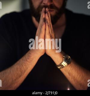 Wir beten hart um Erlösung. Nahaufnahme eines Mannes, dessen Hände im Gebet zusammengeklemmt sind. Stockfoto
