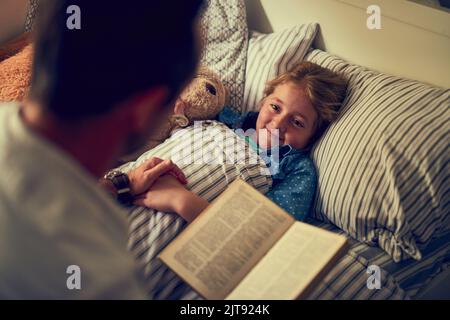 Shell haben einige magische Träume heute Abend. Ein Vater eine Schlafenszeit Geschichte zu seiner kleinen Tochter zu Hause zu lesen. Stockfoto