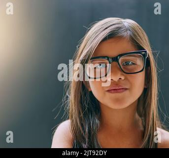 Shes ein selbstbewusstes kleines Cutie. Studioportrait eines kleinen Mädchens, das eine Brille vor dunklem Hintergrund trägt. Stockfoto