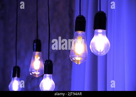 Lampen im Retro-Stil hängen in der Nähe der alten Backsteinmauer in Stimmung, Retro-Beleuchtung, Inneneinrichtung, Retro-Glühbirne Stockfoto