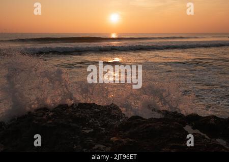 Die Wellen stürzen bei Sonnenuntergang über dem Atlantik in Portugal auf die Felsen Stockfoto