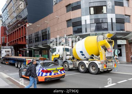 BMW Polizeiauto und Transportbetontruck im Verkehr im Stadtzentrum von Sydney, NSW, Australien Stockfoto