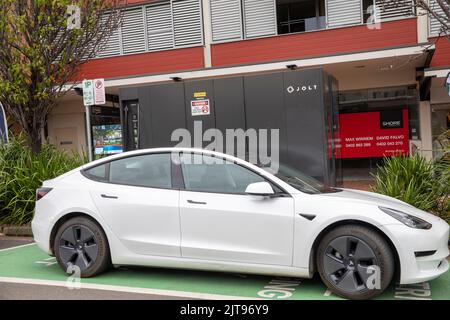 Weißes Tesla-Modell 3, das auf einem öffentlichen Jolt EV-Ladegerät in Mona Velle, Sydney, NSW, Australien geladen wird Stockfoto