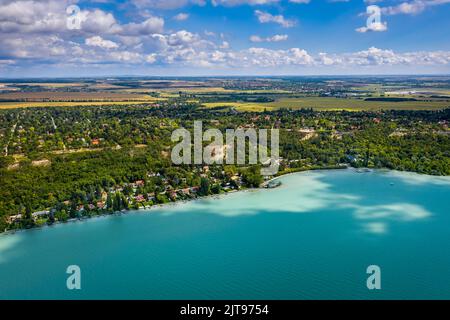 Balatonacarattya, Ungarn - Luftpanorama von Balatonacarattya an einem sonnigen Sommertag mit türkisfarbenem Plattensee, blauem Himmel und Wolken Stockfoto