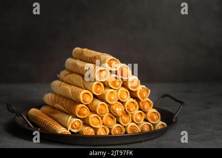 Rockige, knusprige Röhrchen mit Kondensmilch auf einem Metalltablett Stockfoto