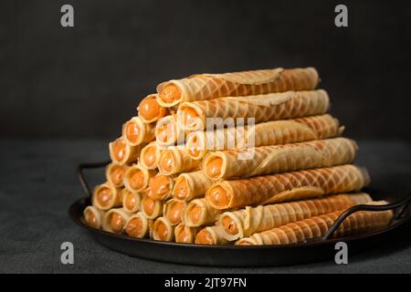 Rockige, knusprige Röhrchen mit Kondensmilch auf einem Metalltablett Stockfoto