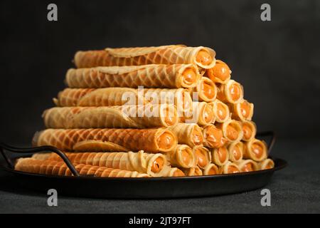 Rockige, knusprige Röhrchen mit Kondensmilch auf einem Metalltablett Stockfoto
