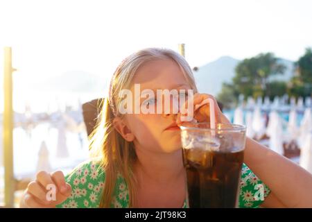 Kleines Mädchen, das im Café im Freien Limonade mit Stroh trinkt Stockfoto