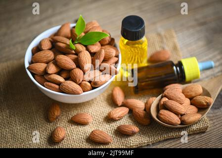 Mandelöl und Mandelnüsse auf der Schüssel, leckeres süßes Mandelöl in Glasflasche, geröstete Mandelnuss für gesunde Ernährung und Snack Bio-Pflanzenöle Stockfoto