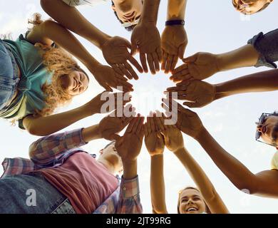 Multirassisches Team glücklicher junger Freunde, die lächeln und ihre Hände zusammenbringen Stockfoto