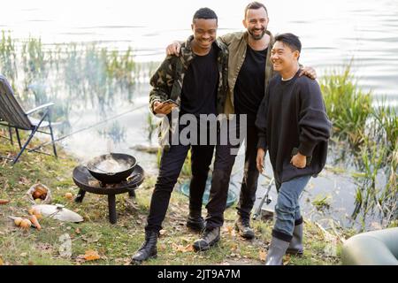 Drei multirassische männliche Freunde, die Spaß beim Angeln haben Stockfoto