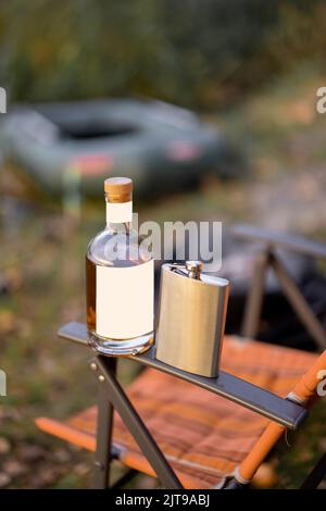 Flasche mit starkem Alkohol und Kolben auf Gummiboot Stockfoto