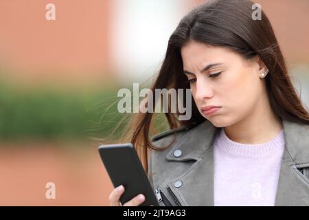 Gelangweilter Teenager überprüft das Smartphone auf der Straße Stockfoto