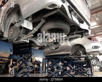 Pickup-LKW und Limousine im Prozess der Änderung der Räder auf dem Auto Aufzüge in einer Garage. Die Radnabe im Fokus. Stockfoto