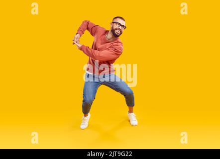 Fröhlicher, fröhlicher junger Mann in moderner Freizeitkleidung, tanzt und hat Spaß im Studio Stockfoto